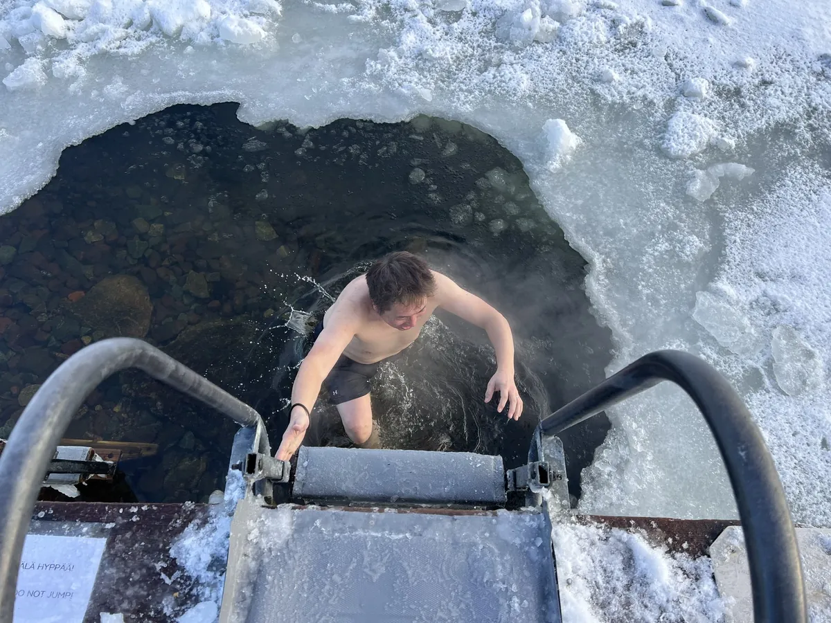 湯気の立つ氷穴から上がる男性、本場の水風呂
