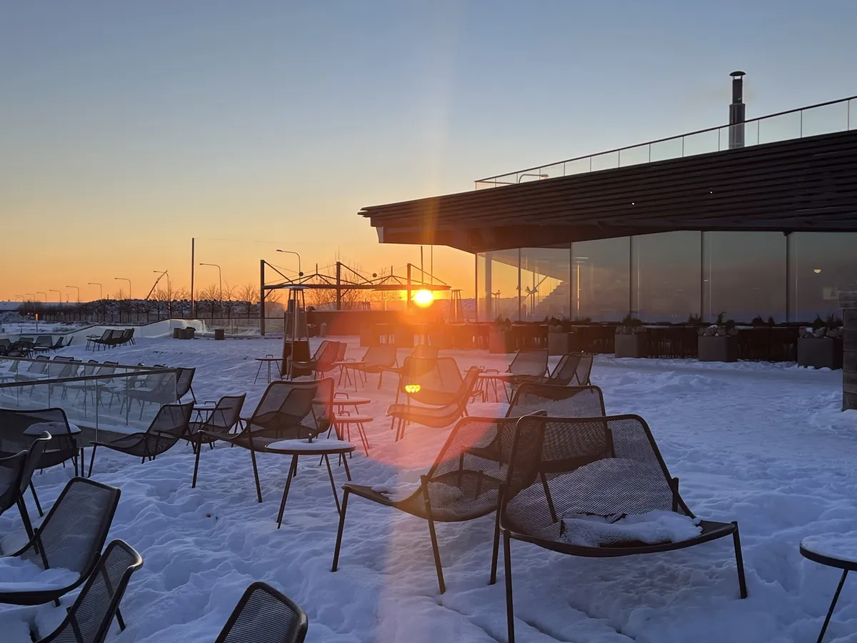 雪のテラスに並ぶ外気浴の椅子と冬の夕日